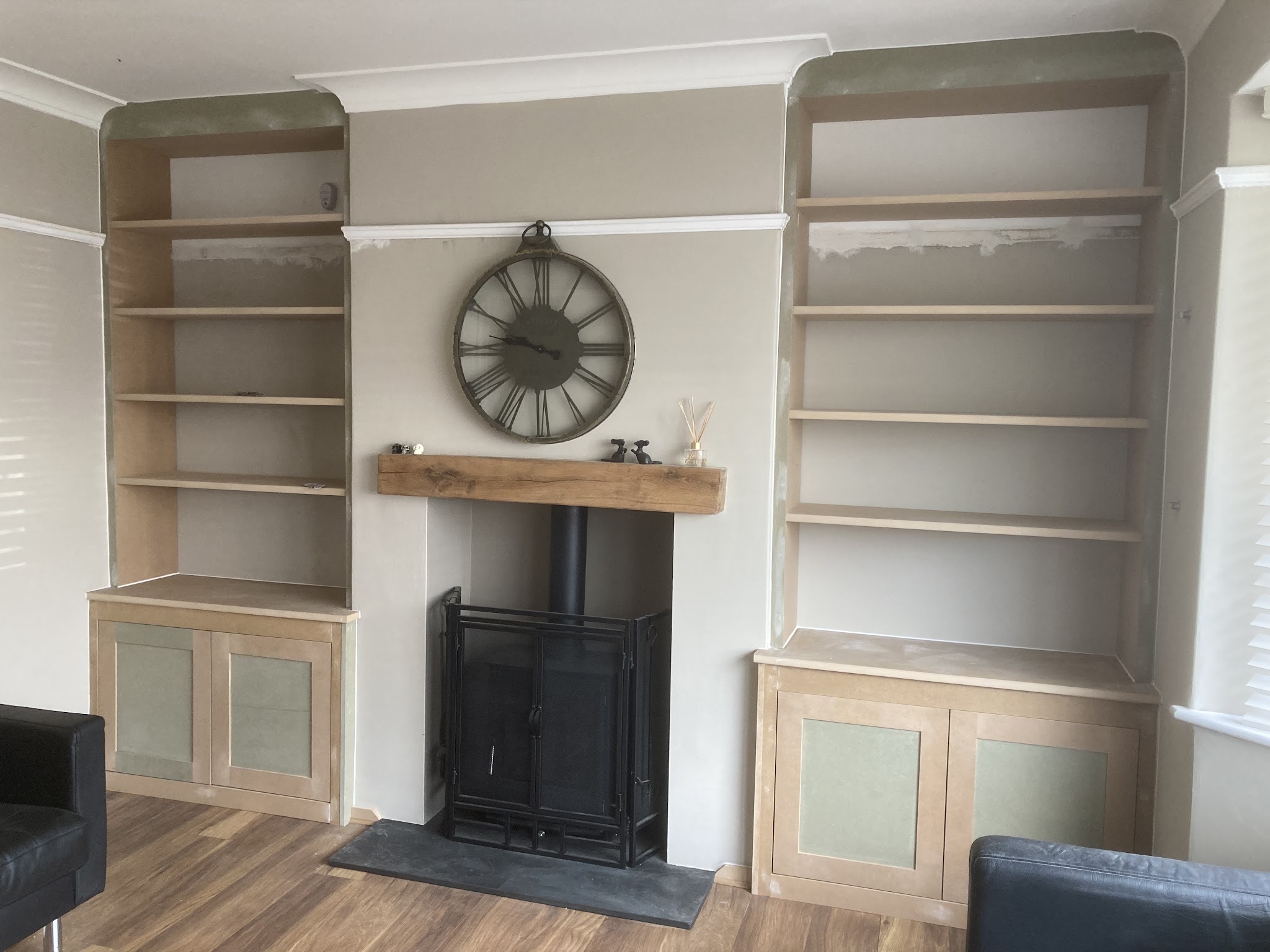 Bespoke alcove cupboards and shelves fitted around a fireplace, before painting