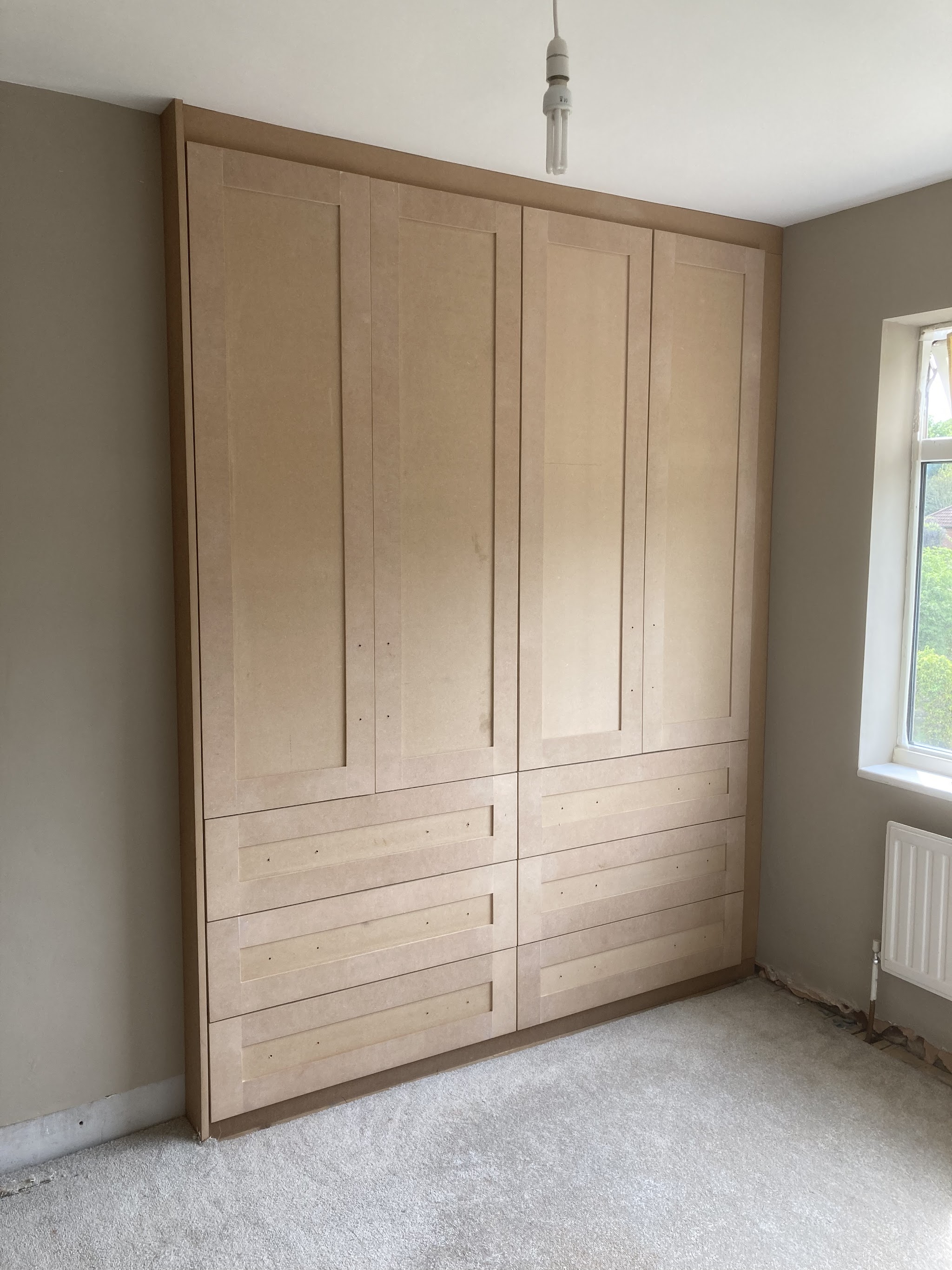 A fitted timber wardrobe with cupboards and drawers, ready for finishing